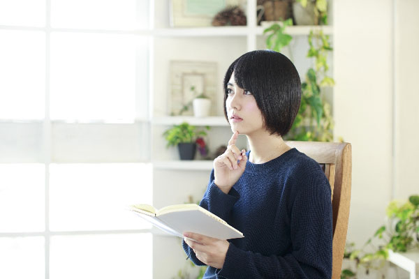 本を片手に考える女性